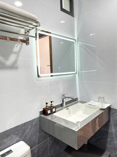 a bathroom with a sink and a mirror and a toilet at Avenue Hotel VangVieng in Vang Vieng