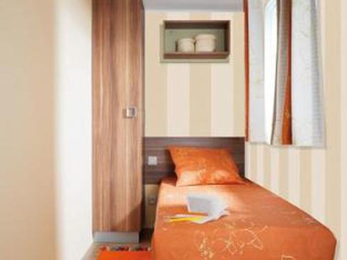 a bedroom with a bed with a book on it at Mobil-home avec Terrasse, 3 Chambres, 4 Personnes - API-1-52-1131 in Saint-Rome-de-Tarn