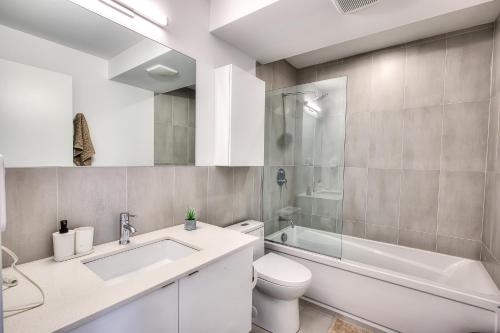 Tiny Penthouse Big Balcony Central & Cozy في مونتريال: حمام مع حوض ومرحاض وحوض استحمام