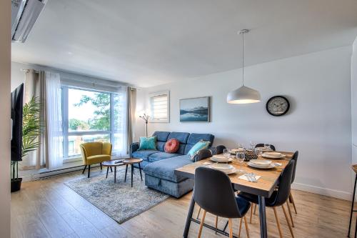Tiny Penthouse Big Balcony Central & Cozy في مونتريال: غرفة معيشة مع أريكة زرقاء وطاولة