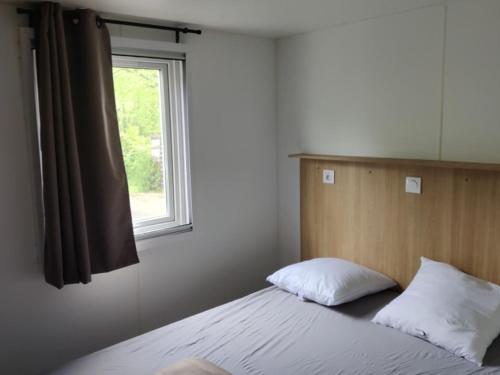 Mobil Home avec Terrasse - 4 personnes - API-1-52-1165 في Saint-Rome-de-Tarn: غرفة نوم بها سرير مع نافذة