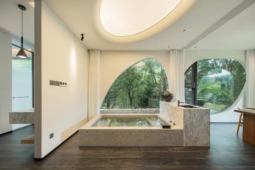 ein großes Zimmer mit einer Badewanne mit einem großen Fenster in der Unterkunft Mogan Mountain Mantian Eco Hotel in Deqing