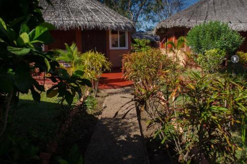 a house with a thatch roof and a yard with plants at Edena Kely in Mahajanga