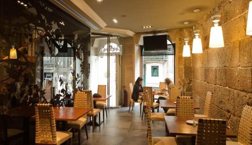 ビーゴにあるHotel Puerta Gamboaのテーブルと椅子が備わるレストランで、背景に人がいる