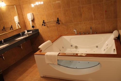 a bathroom with a large tub and a sink at Hotel Don Carlo in Broni