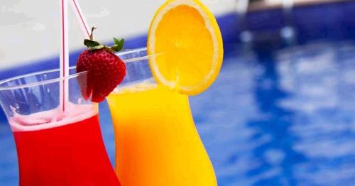 a drink with a strawberry and an orange slice next to a pool at Atlântico Golden Apart Hotel in Santos