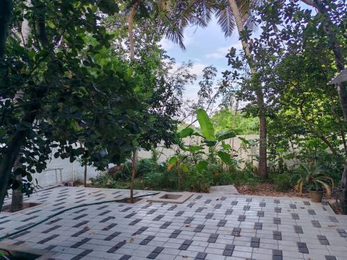 a garden with trees and a brick patio at The Sparrow House 2BHK Ground Floor in Kumbakonam