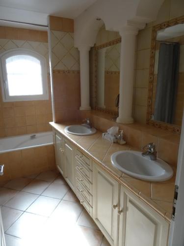 ein Badezimmer mit zwei Waschbecken und einer Badewanne in der Unterkunft Les Lauriers Blancs in Callas