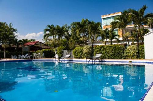 a large swimming pool with chairs and palm trees at Yopo Resort in Yopal