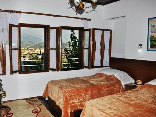 a bedroom with two beds and windows with a view at Guest house Hava Baci in Berat