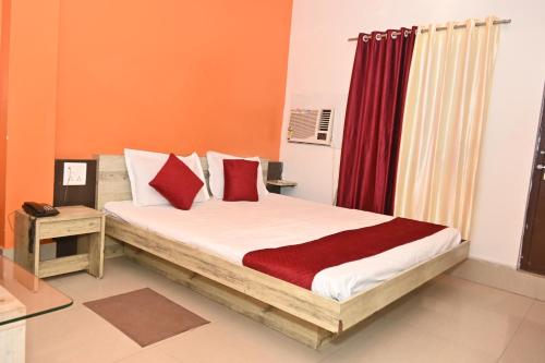 a bedroom with a bed with red and white pillows at Maurya Royal in Sasarām