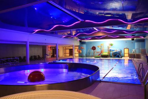 a swimming pool in a building with blue lights at Hotel Continental in Krynica Morska