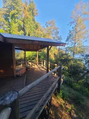 een hut met een houten terras in het bos bij Cabaña Yoka - Orilla de Lago in Pucura