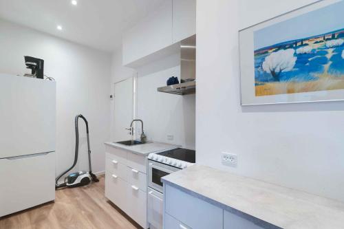 Una cocina blanca con fregadero y refrigerador. en Holiday Apartment At Beautiful Solgaarden 8, en Svaneke