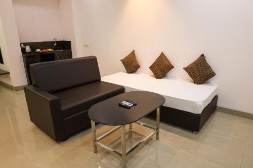 a room with a bed and a chair and a table at Sairaah Golden Suites, Shirdi in Shirdi