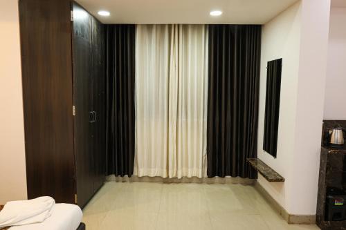 a room with a bed and a window with curtains at Sairaah Golden Suites, Shirdi in Shirdi