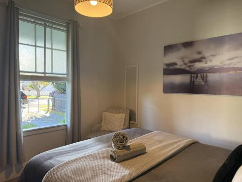 Hawke's Bay Escape - Railway Cottage في هاستينغز: غرفة نوم بها سرير ونافذة