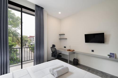 Dieses weiße Zimmer verfügt über ein Bett, einen Schreibtisch und einen TV. in der Unterkunft Cove Legacy in Jakarta