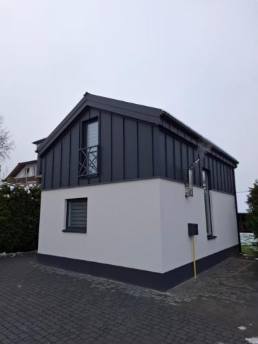 een zwart-wit gebouw met een grote garage bij TINY HOUSE domek do wynajęcia in Olsztyn