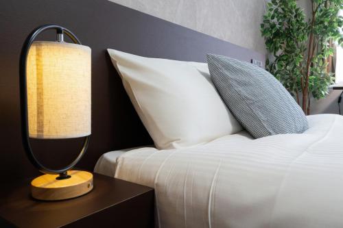 a bedroom with a bed and a lamp on a night stand at Residence Hotel Sapporo Susukino in Sapporo