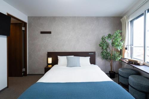 a bedroom with a large bed with a blue blanket at Residence Hotel Sapporo Susukino in Sapporo
