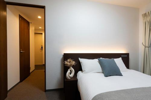 a bedroom with a white bed and a mirror at Residence Hotel Sapporo Susukino in Sapporo