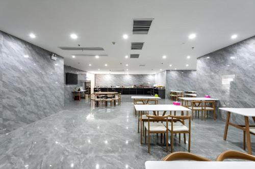 ein Restaurant mit Tischen und Stühlen in einem Raum in der Unterkunft Borrman Hotel Jiangyin Zhouzhuang in Xiwujieqiao