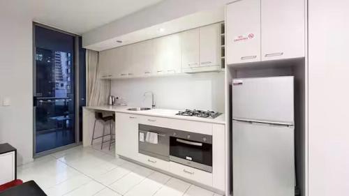 Cozy Studio in the heart of CBD C4 في بريزبين: مطبخ ابيض مع موقد وثلاجة