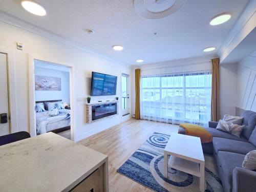 a living room with a couch and a tv at Family Modern 1BR and Den Condo - Apartment with City View, Downtown, Balcony, Free Parking & In-Suite Laundry! in Calgary