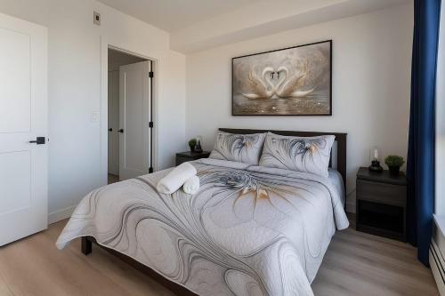 a bedroom with a large bed with a painting on the wall at Family Modern 1BR and Den Condo - Apartment with City View, Downtown, Balcony, Free Parking & In-Suite Laundry! in Calgary