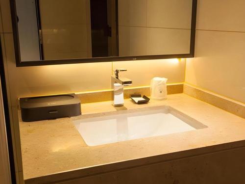 um lavatório de casa de banho com um grande espelho por cima em City Comfort Inn Suzhou Wujiang Development Zone Yundong em Suzhou