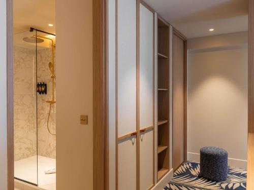 ein begehbarer Kleiderschrank mit einem blauen Hocker im Badezimmer in der Unterkunft Grand Hotel Beauvau Marseille Vieux-Port - MGallery Collection in Marseille