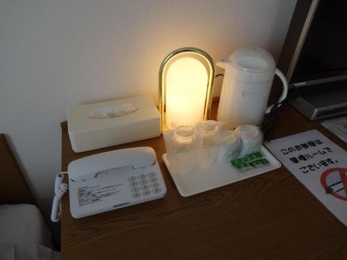 a desk with a telephone and a lamp on it at Hotel Koshien in Nishinomiya