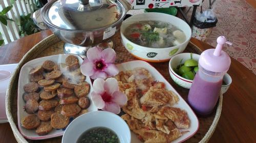 a table with a plate of food and a bowl of soup at Lampang Lanna Home in Lampang