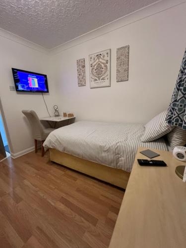 a bedroom with a bed and a table and a tv at The Bungalow by SJP - Twin Room in Kettering
