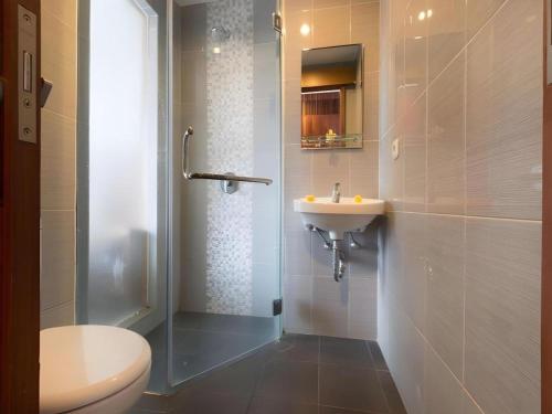 a bathroom with a toilet and a sink and a shower at Hadi Poetra Hotel in Kuta