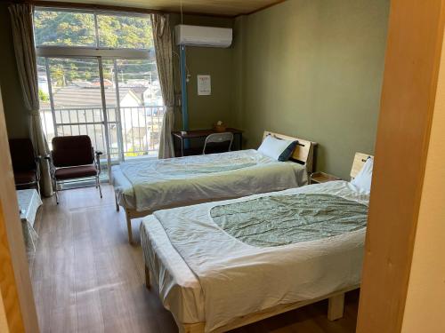 a hotel room with two beds and a balcony at 安房リゾート旅館 臨海臥龍 in Kamogawa