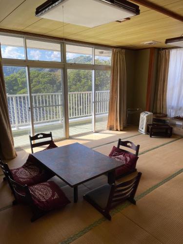 a table and chairs in a room with a large window at 安房リゾート旅館 臨海臥龍 in Kamogawa