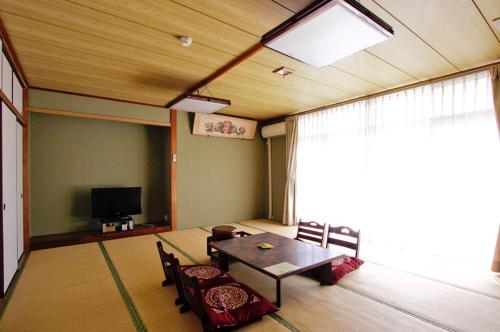 a room with a table and chairs and a television at 安房リゾート旅館 臨海臥龍 in Kamogawa