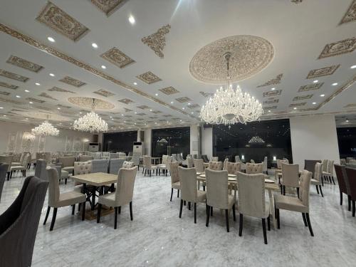 a dining room with tables and chairs and chandeliers at Regency Suites in Lahore