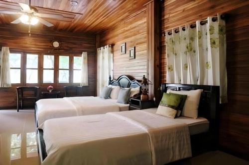 2 letti in una camera con pareti e finestre in legno di Ban Noi Resort Phrae a Sop Sai
