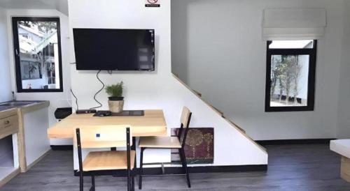 a dining room with a table and a tv on a wall at Khao Yai the kids adventure in Ban Tha Maprang