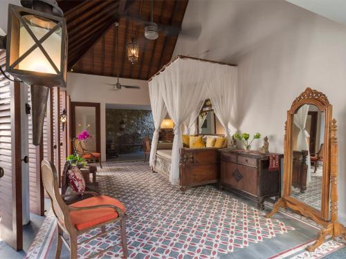 a bedroom with a canopy bed and a mirror at Des Indes Villas in Seminyak