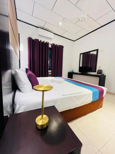 a bedroom with a bed and a table with a stool at Seaport Negombo in Negombo