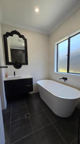 a bathroom with a large white tub and a sink at Brand New Home with Pool in Lyndoch