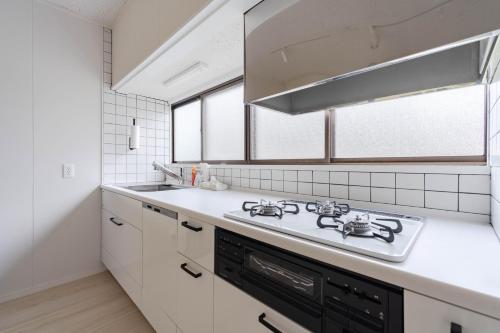 a white kitchen with a stove and a sink at Hakoshimizu Retreat - 10mins walk to Zenkoji in Nagano