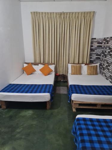 two beds in a room with a window at Bunty's " Free pickup from kandy" in Kandy