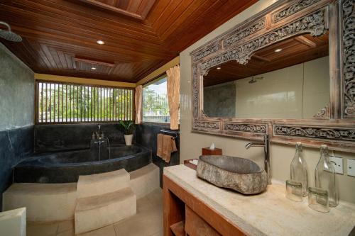 ein Badezimmer mit großer Badewanne und Waschbecken in der Unterkunft Villa Mahayoni in Bedahulu