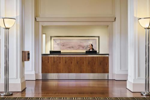 a woman is sitting at a desk in a room at Hyatt Hotel Canberra - A Park Hyatt Hotel in Canberra