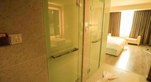 吐鲁番Jinjiang Metropolo Hotel - Turpan Administration Center的一间带玻璃门的浴室,通往一间卧室